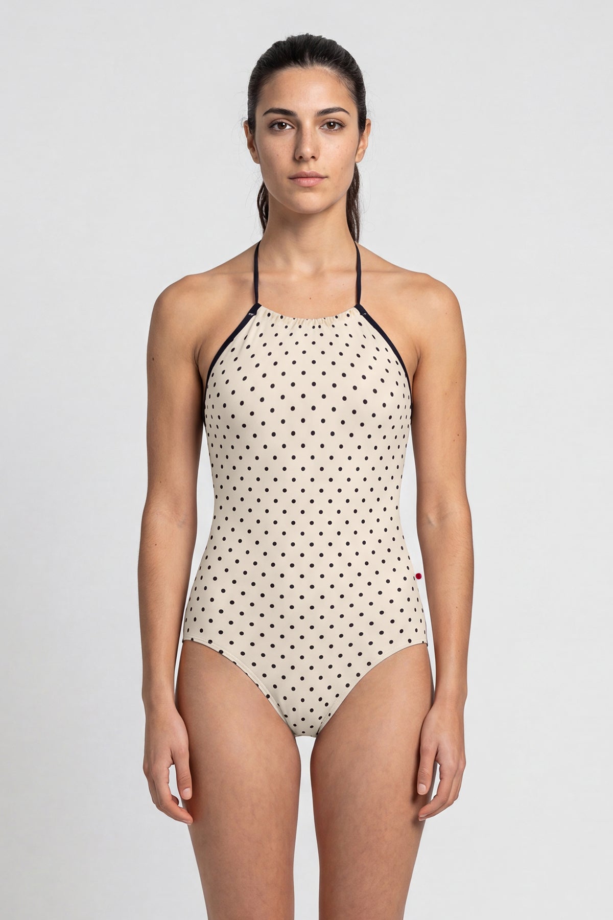 AI-generated model. Monique leotard, all-over cream polka-dot with a black halter neckline.