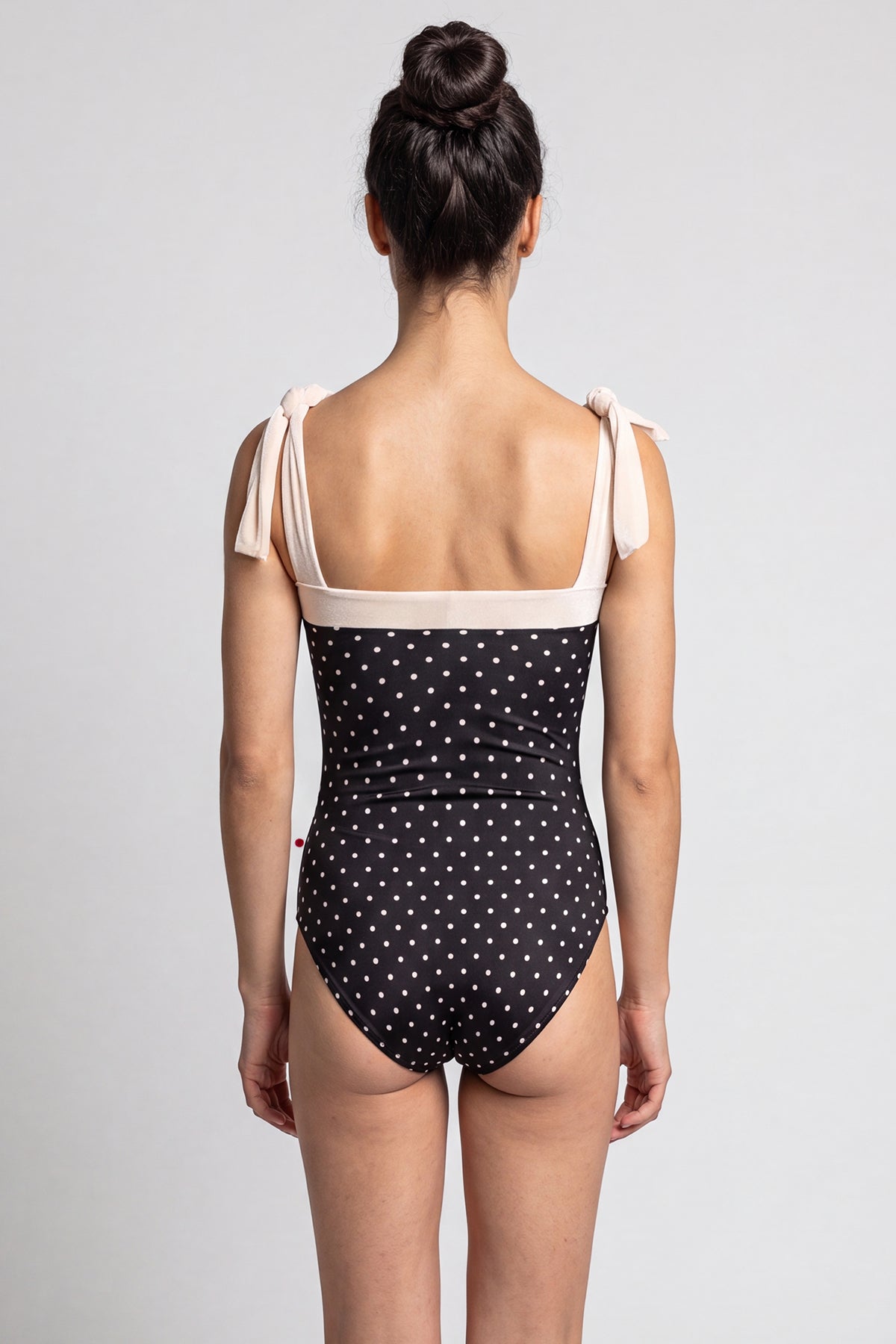 AI-generated model. Mimi leotard, black T-Lunares polka-dot body with a blush square neckline and knotted tie shoulder straps.