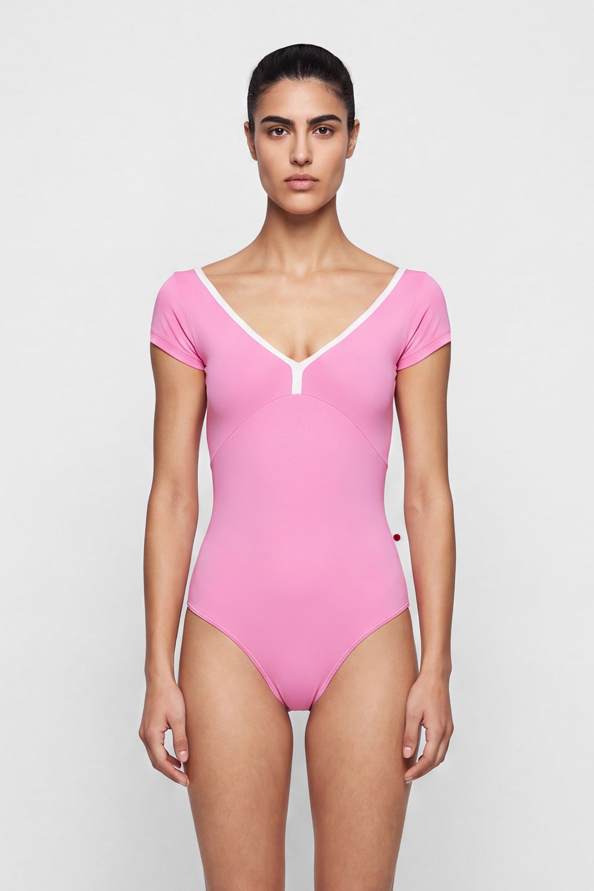 AI-generated model. Alicia leotard, bright pink with cap sleeves and a V-neck with white centre trim.
