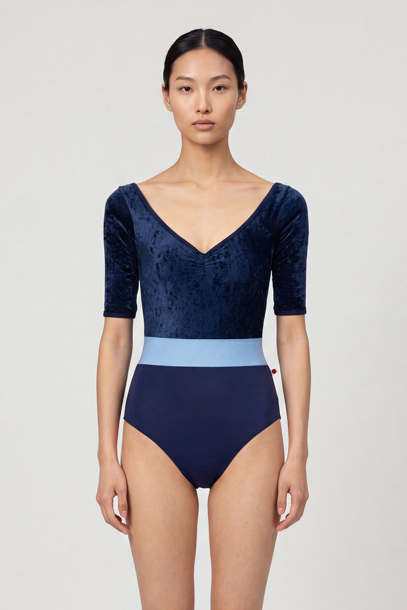 AI-generated model. Lucy leotard, navy crushed-velvet elbow-sleeve bodice with a light-blue waistband and a navy body, V-neck.