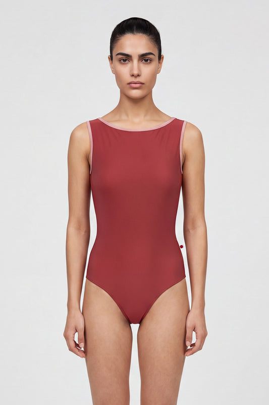 AI-generated model. Sofiane leotard, brick-red with a high boat neckline and pink strap trim.