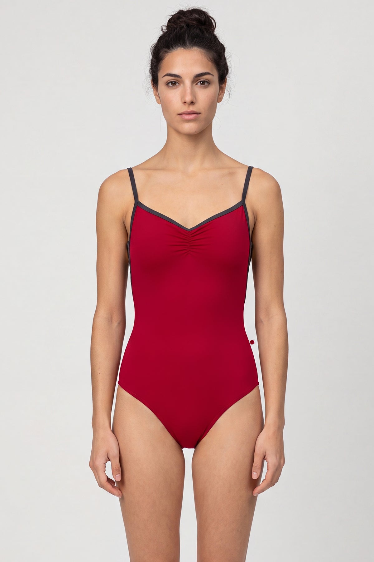 AI-generated model. Tamara leotard, deep crimson with a pinch-front bust, charcoal straps and neckline trim.