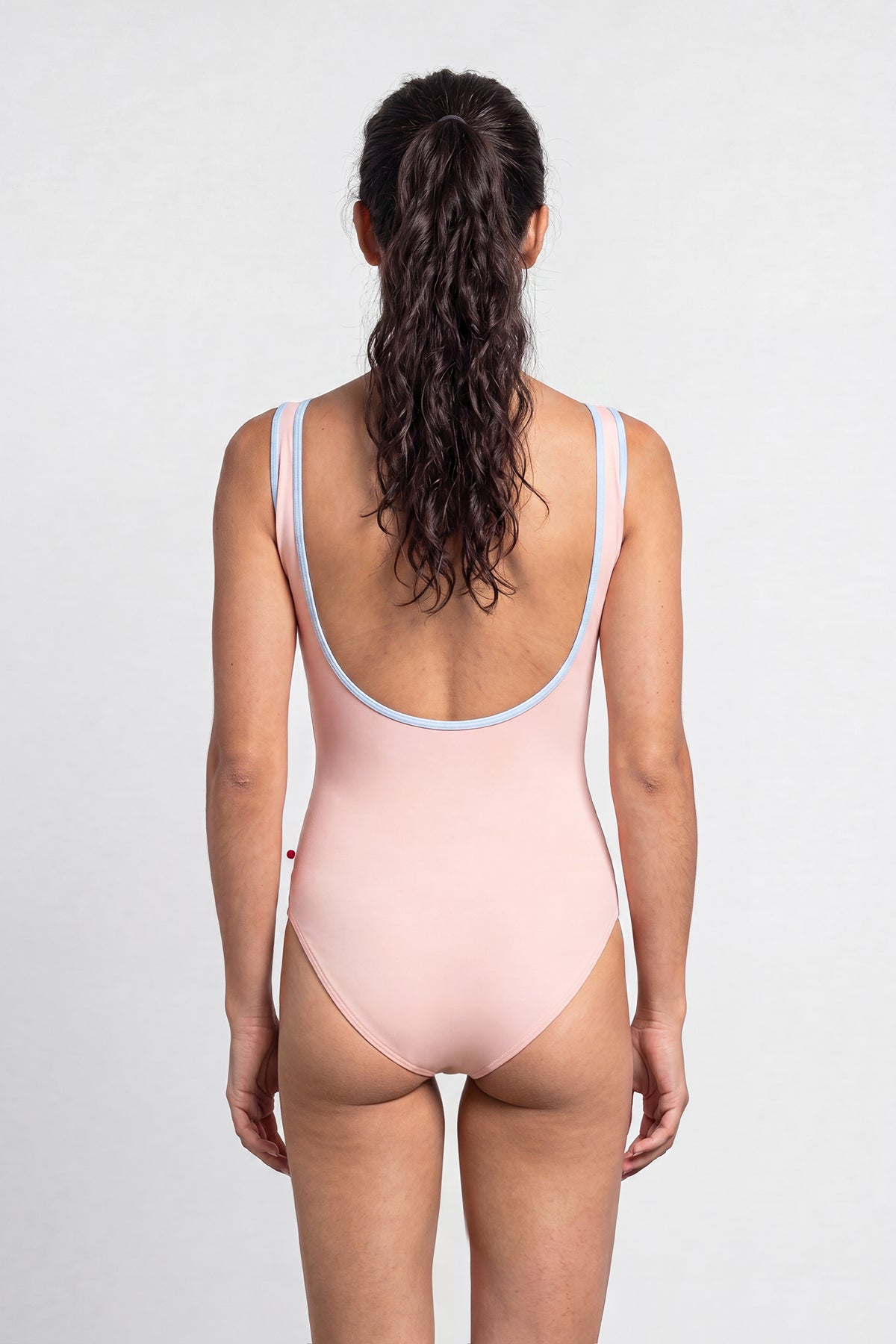 AI-generated model. Sofiane leotard, blush-pink with a contrasting pale-blue neckline trim.